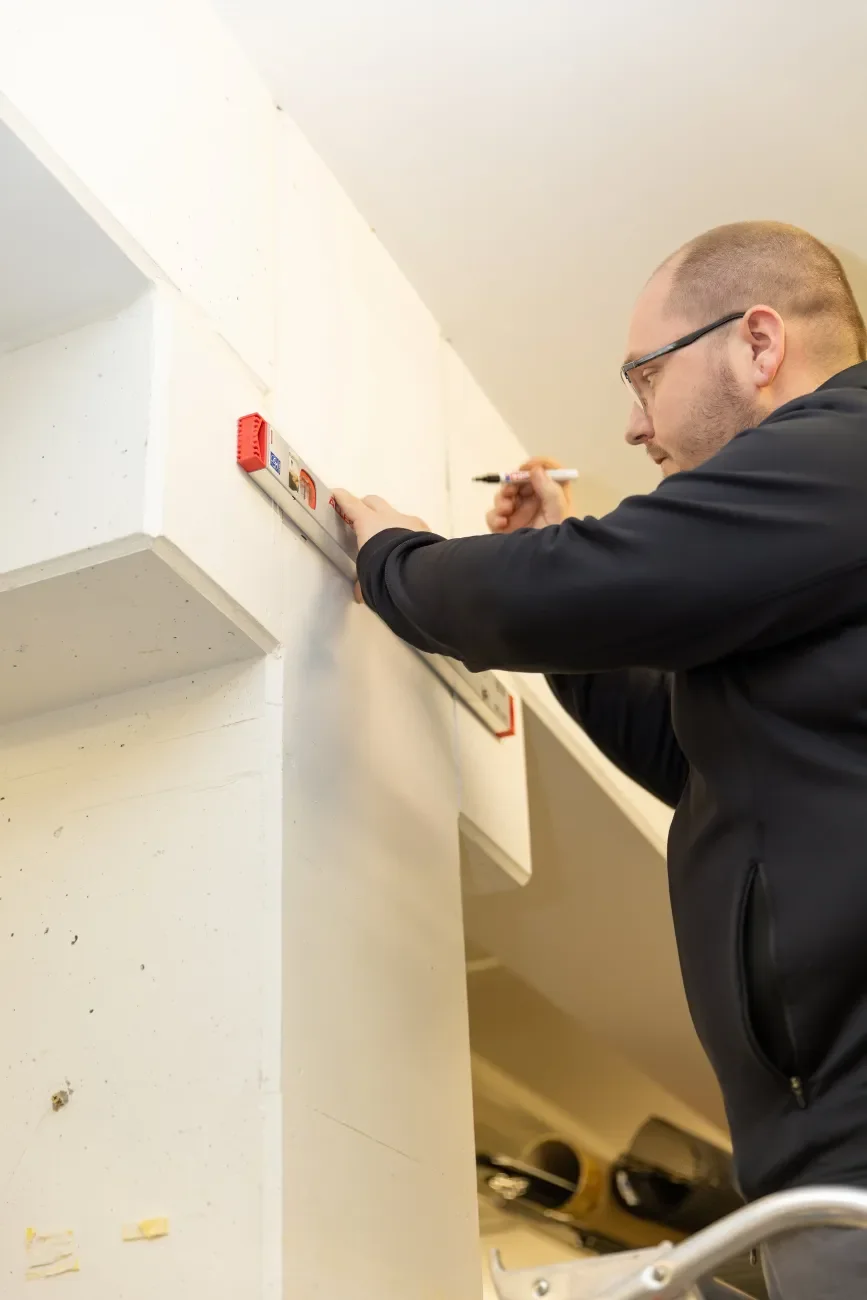 Mann beim Vermessen einer Wand mit Wasserwaage