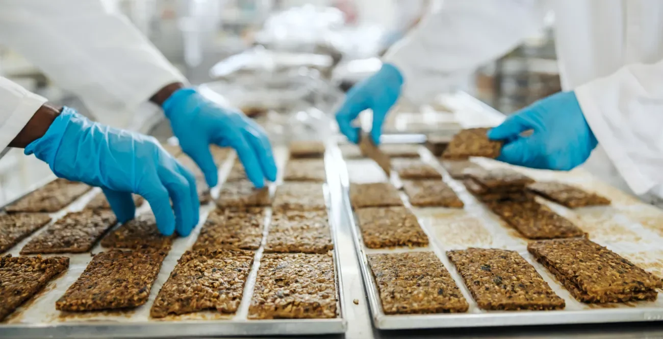 Haferriegel werden auf Blechen kontrolliert in Produktionshalle