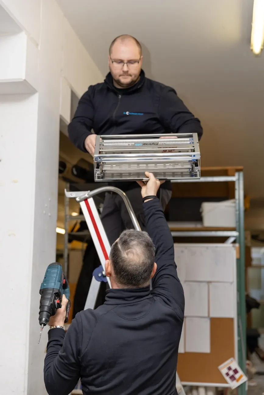 Zwei Schädlingsbekämpfer montieren eine elektrische Fliegenfalle