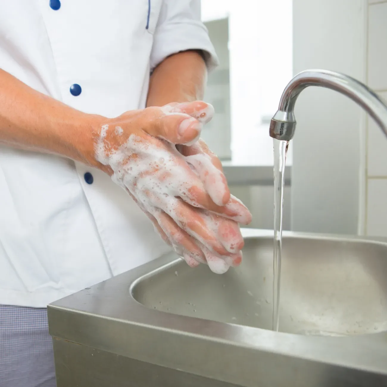 Person in Arbeitskleidung wäscht sich die Hände