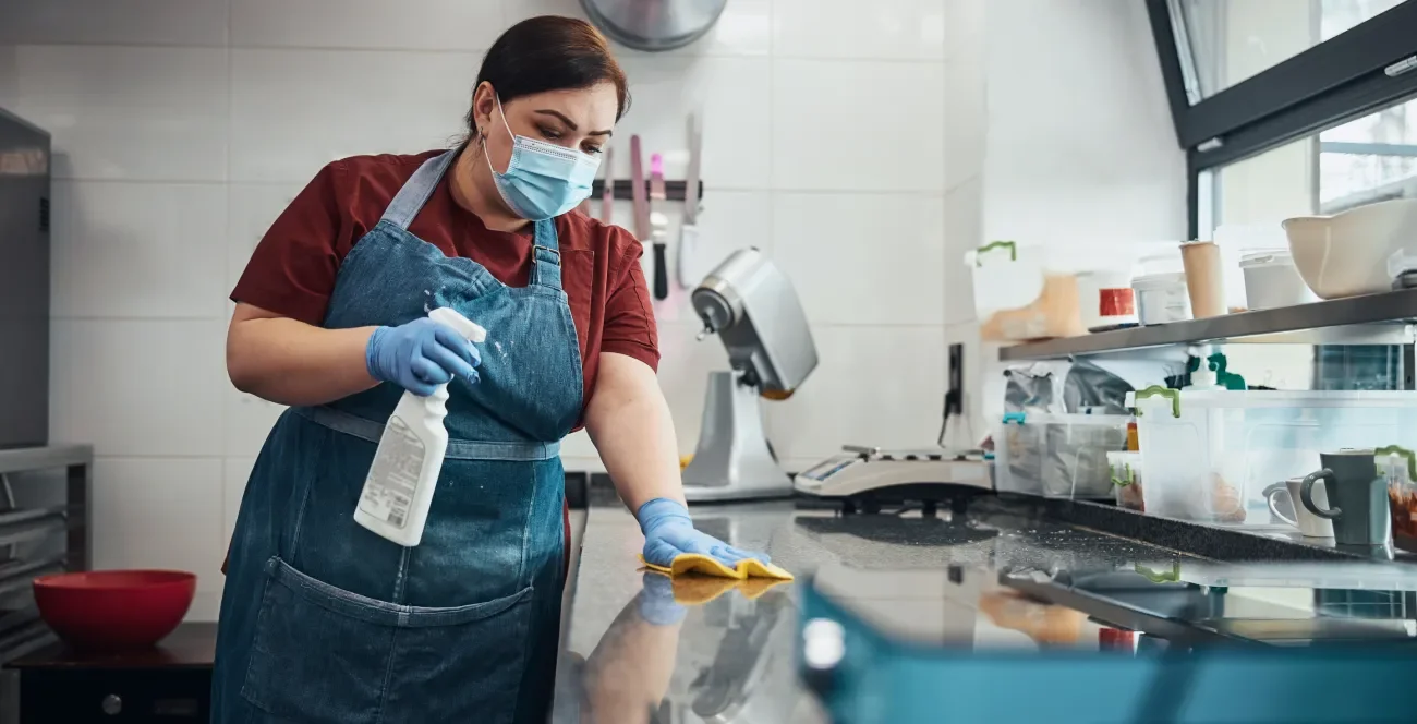 Frau reinigt Arbeitsfläche in Restaurantküche