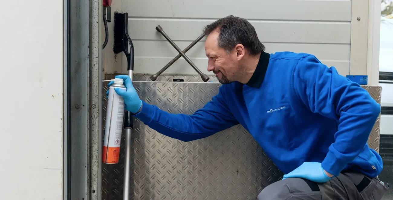 Schädlingsbekämpfer sprüht ein Spray in die Ecken einer Garage