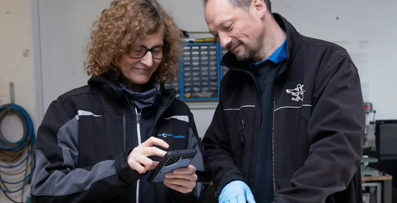 Zwei Schädlingsbekämpfer bei der Arbeit überprüfen etwas auf dem Arbeitshandy