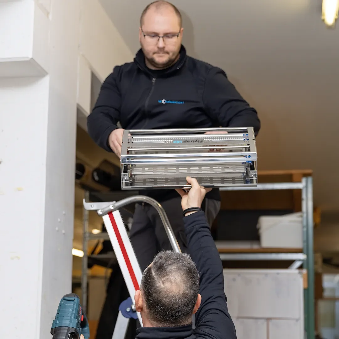 Zwei Schädlingsbekämpfer bringen einen elektrischen Fliegenfänger an der Wand an