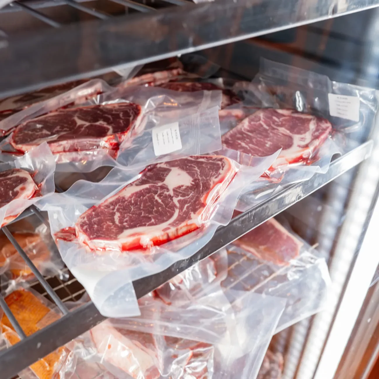 Vakuumierte Fleischstücke mit Label im Kühlschrank