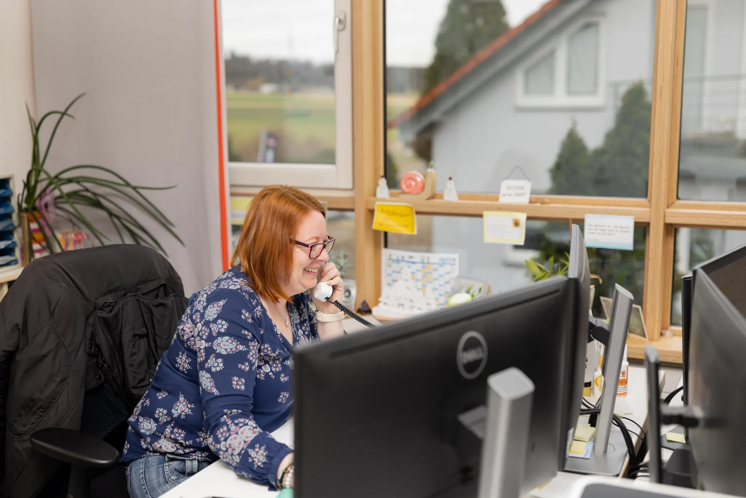 Fröhliche Mitarbeiterin von Der Puschmann am Telefon am Schreibtisch