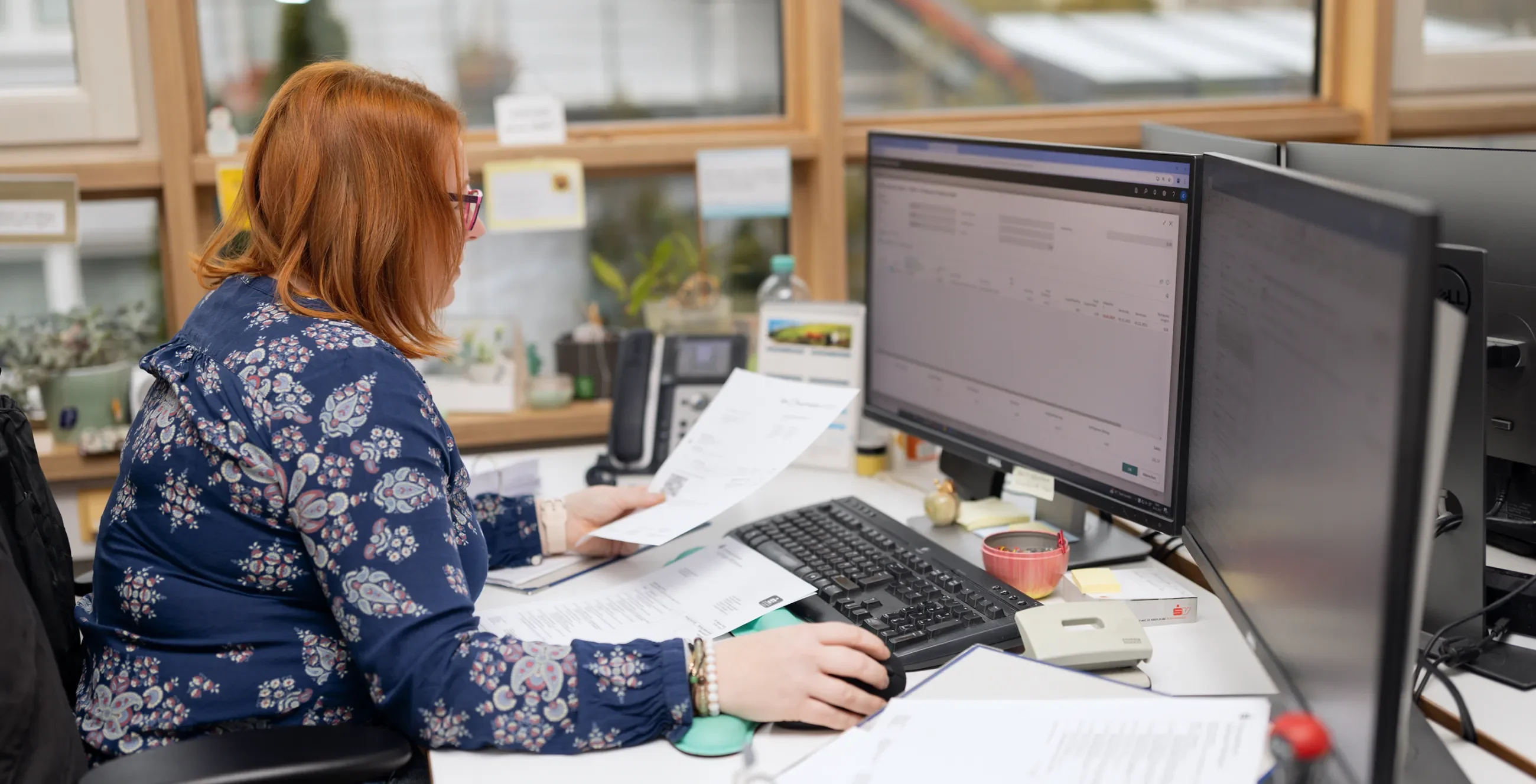 Sachbearbeiterin pflegt Daten von Zetteln am Computer ein